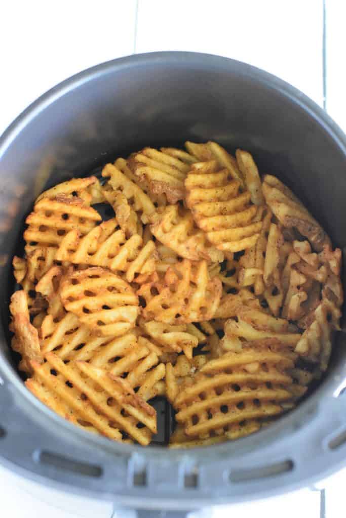 overhead of waffle fries in air fryer after cooking.