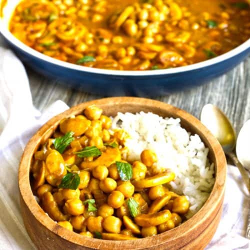 chickpea curry in bowl with rice with more curry in a bowl behind it.