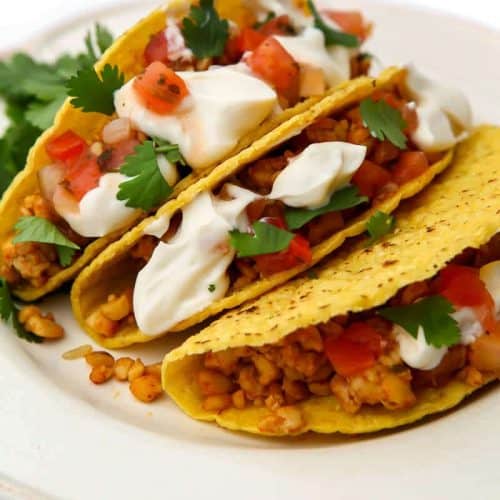 three tempeh tacos on a white plate.