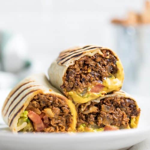 front view of three halves of vegan cheeseburger wrap on a white plate.