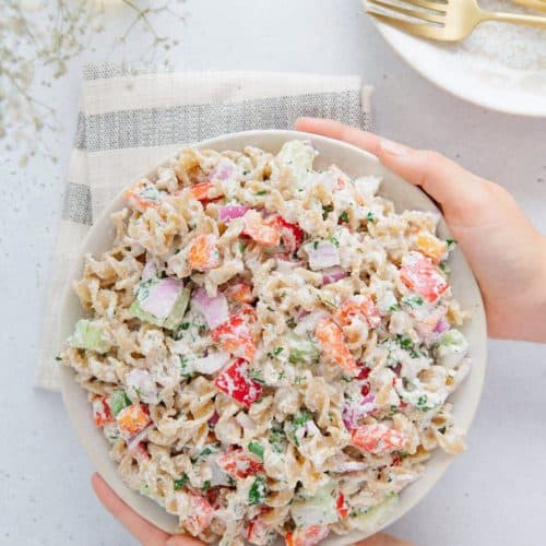 holding bowl of pasta salad with two hands.