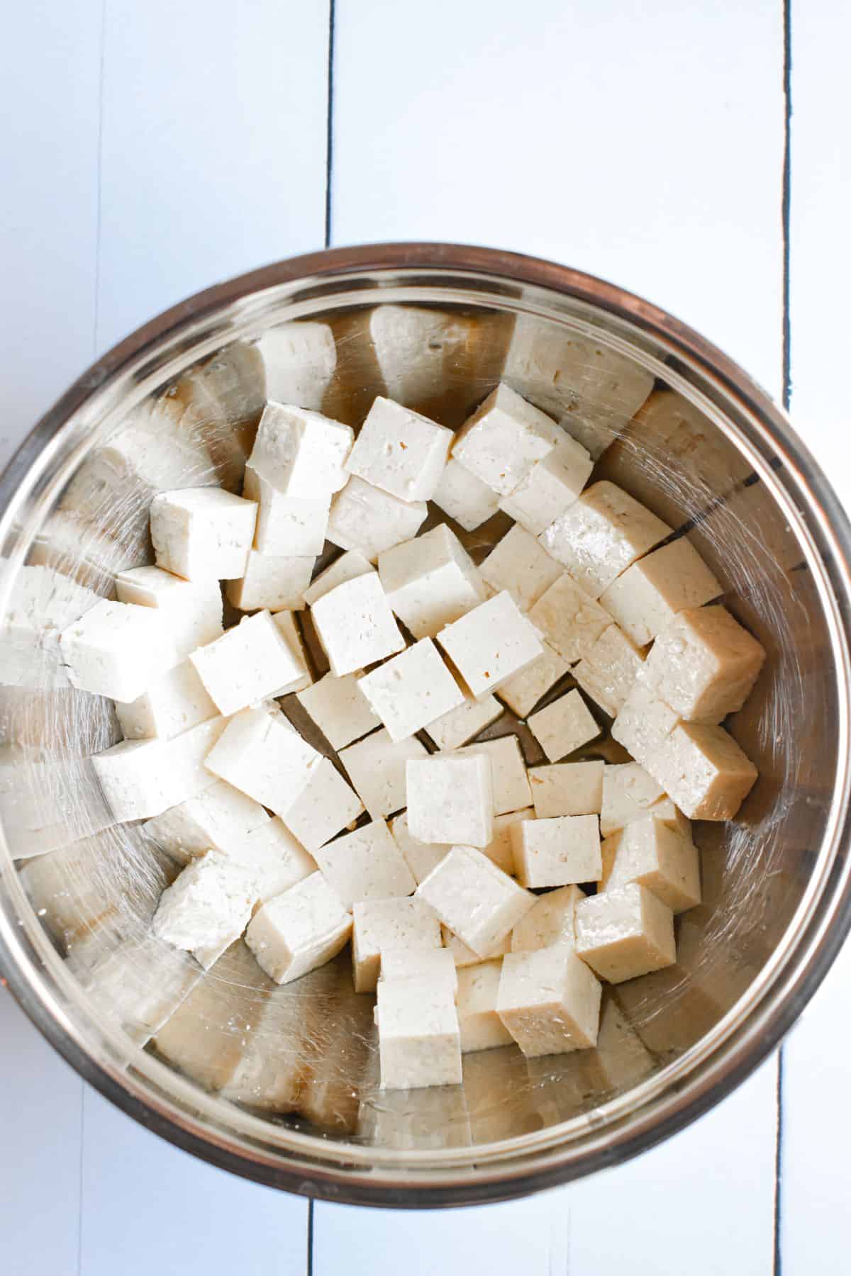 Tofu cut into cubes in a mixing bowl.