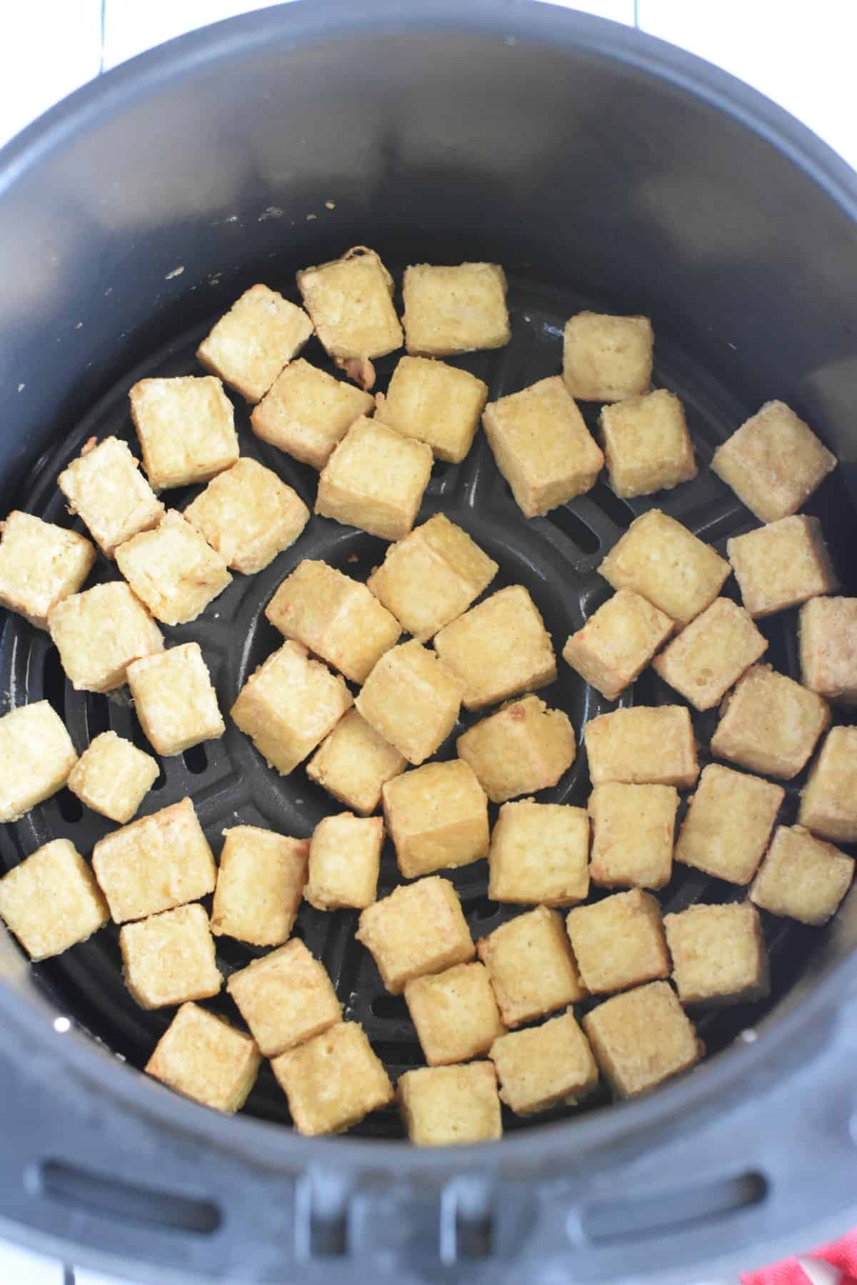 Cooked tofu cubes in an air fryer.