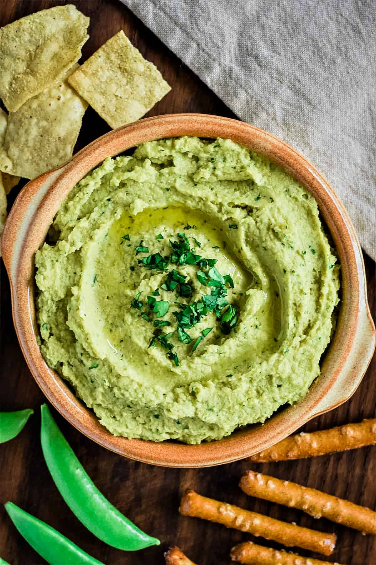 overhead of hummus in a bowl with dipping snacks around it.