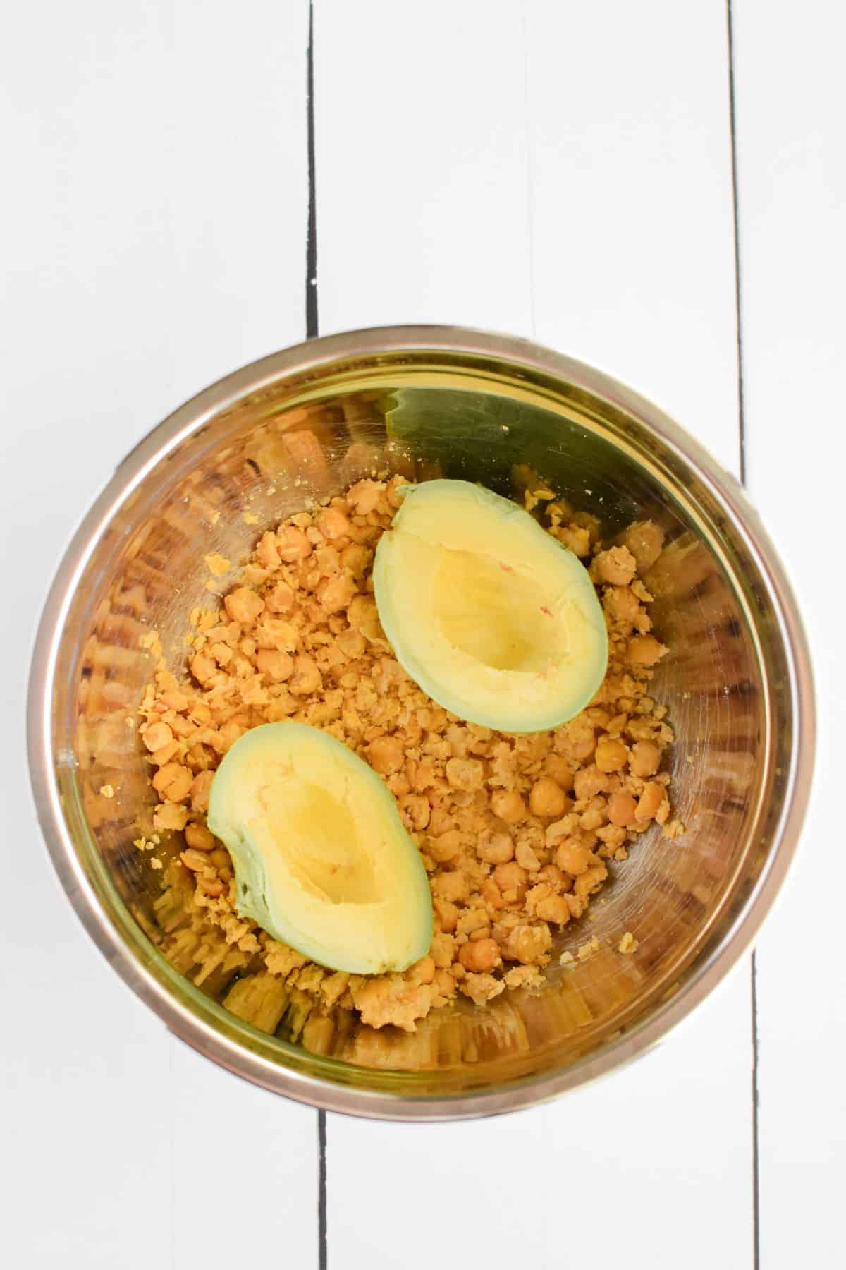 Avocado slices on smashed chickpeas in a bowl.