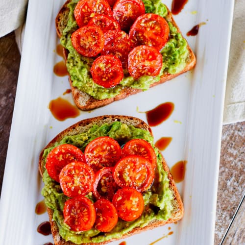 Tomato avocado toast on a white dish.