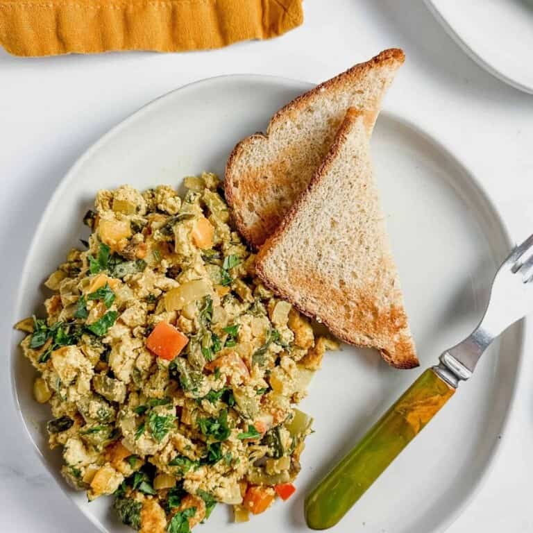 vegan breakfast casserole on a white plate with toast and a fork on the side