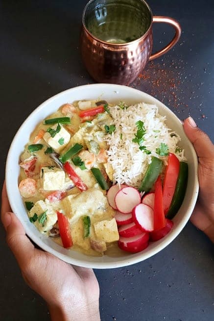Vegan Thai Green Curry served in a bowl with rice and garnishes.