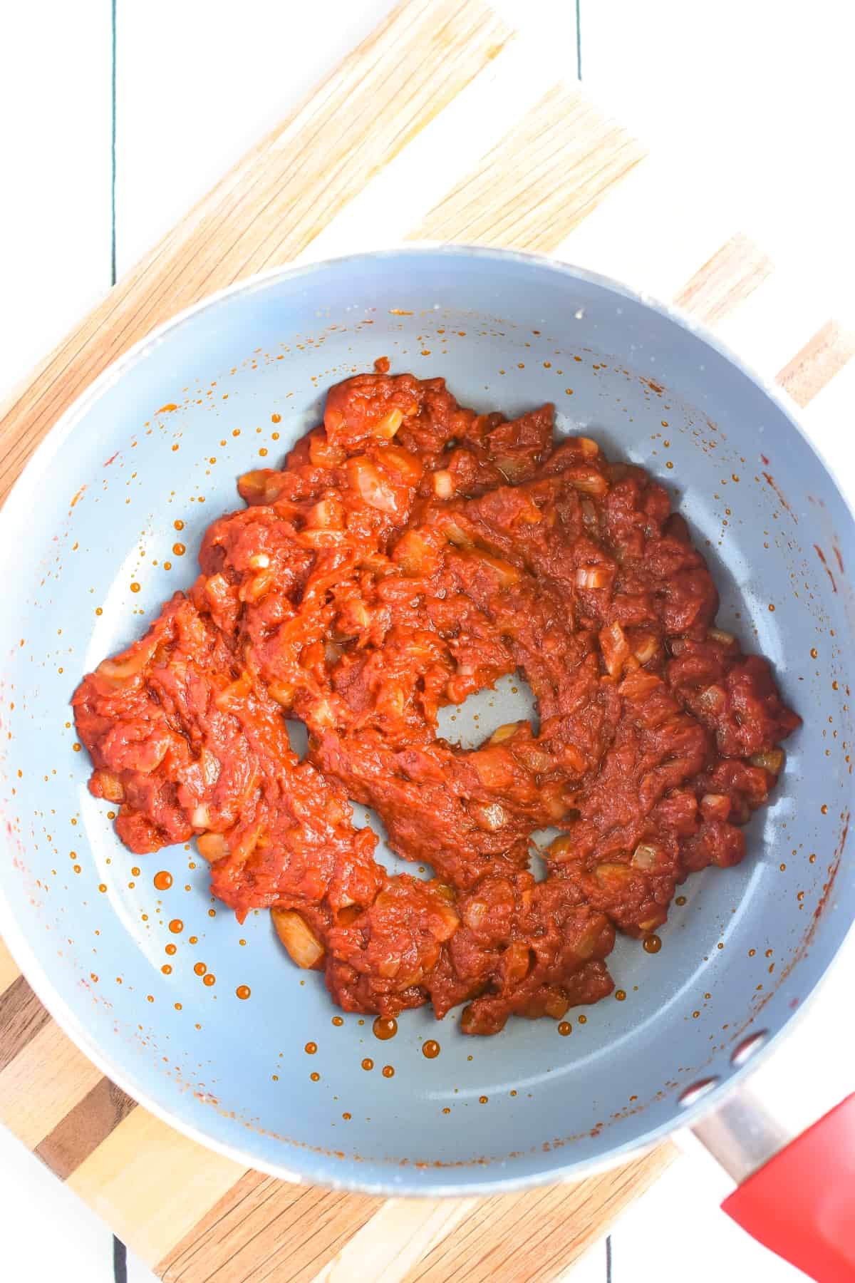 Tomato paste with onions and garlic in a pan.