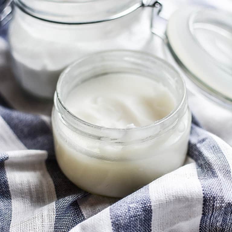 coconut oil in glass jar on kitchen towel.