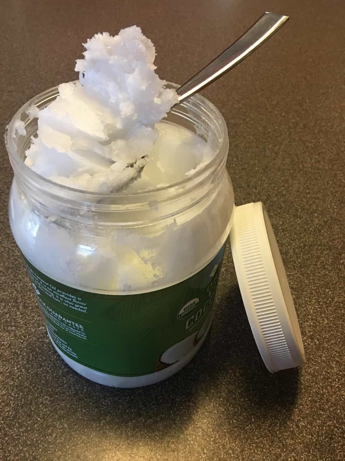 scooping coconut oil out of a jar with a spoon.