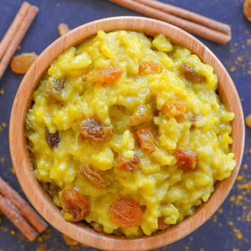 Slow cooker rice pudding with turmeric and cinnamon in a wooden bowl.