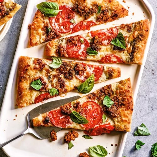 Pizza with Plant Based Walnut Crumble on a dish with a serving spoon.