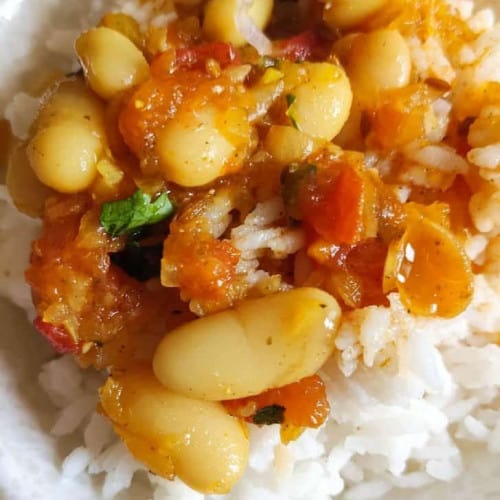 White bean curry over white rice in a bowl.