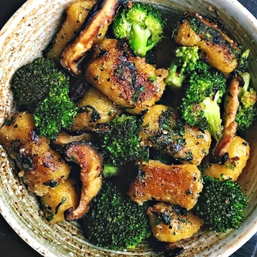 crispy pan fried vegan gnocchi with mushrooms and broccoli in a bowl.