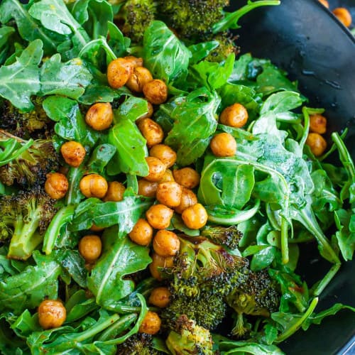 healthy roasted chickpea broccoli arugula salad in a bowl.
