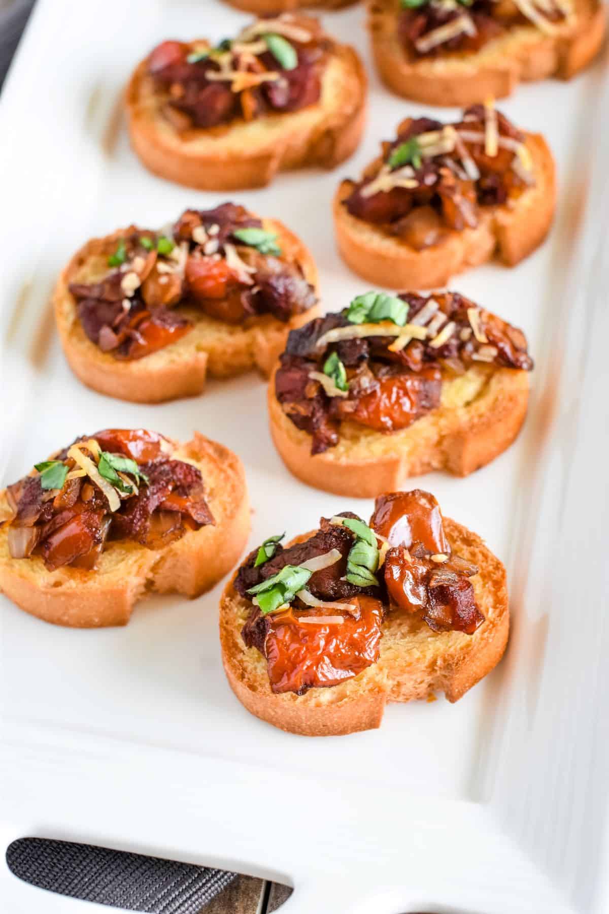 front view of bruschetta on a white serving dish.