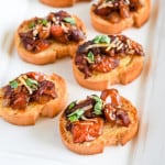 close-up of pieces of bruschetta on a white serving plate.