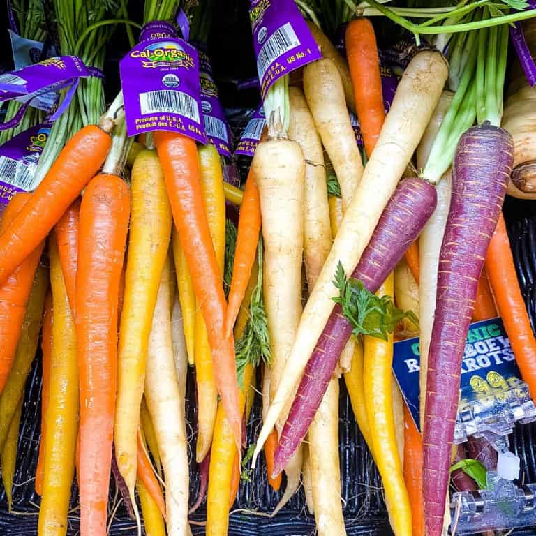 Tri-colored carrots on supermarket shelf.