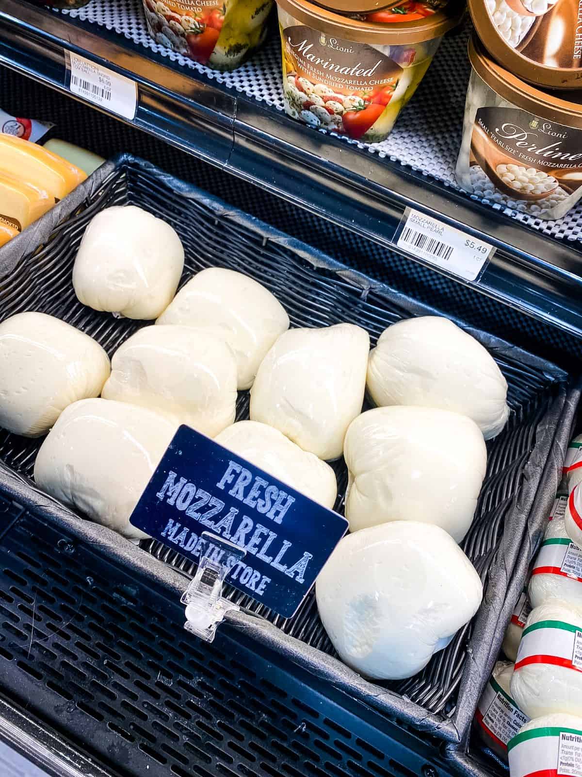 Fresh mozzarella cheese on supermarket shelf.