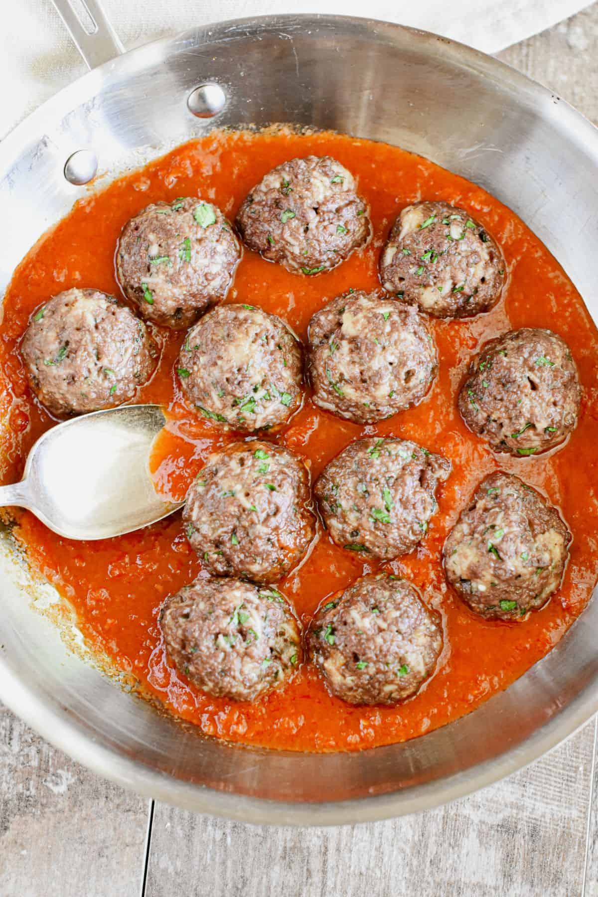 Impossible Burger Meatballs in a pan with a spoon.