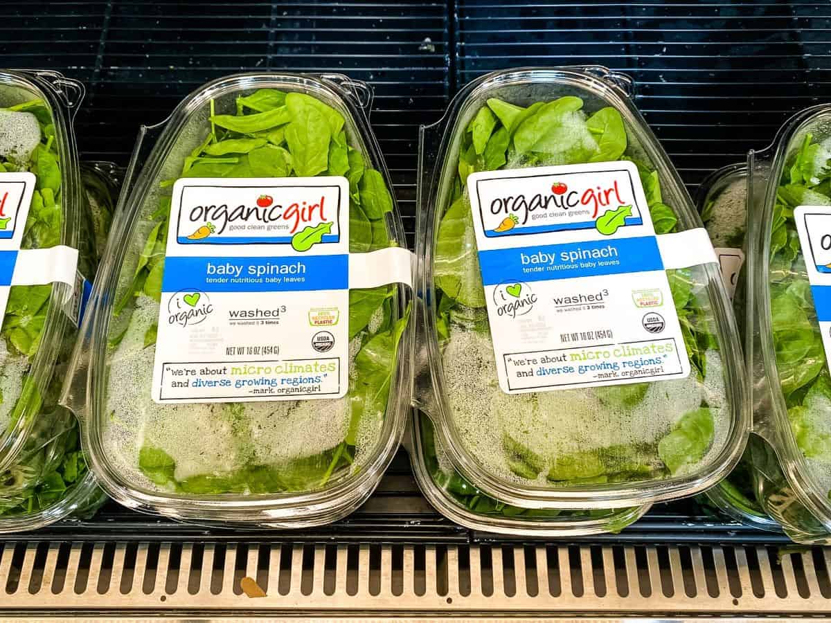 Packages of spinach on a supermarket shelf.