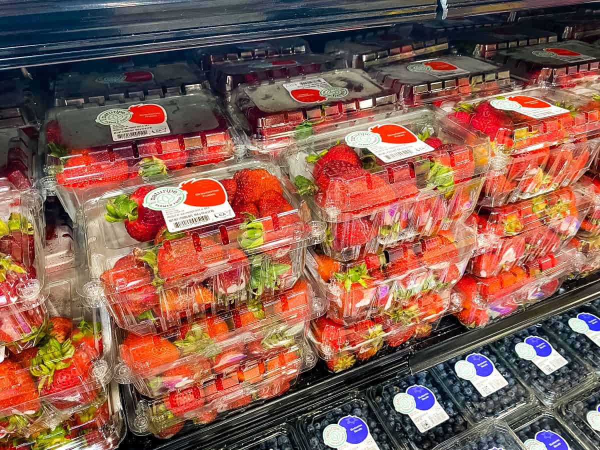 Packages of strawberries on supermarket shelf.
