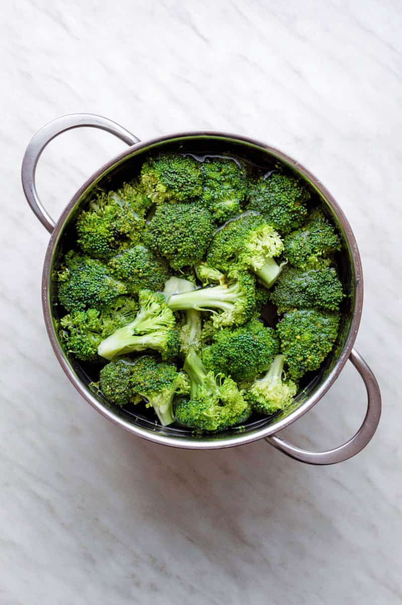 Blanching broccoli in a large stainless-steel pot.