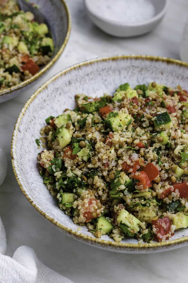 Quinoa salad served in a blue bowl and topped with black pepper.