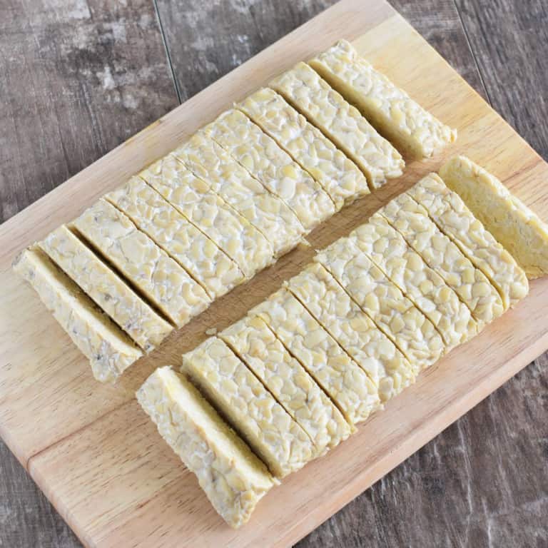 tempeh cut into strips on a wooden board.