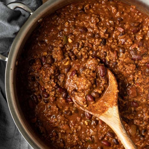 Beyond meat chili in a pan with a wooden spoon.