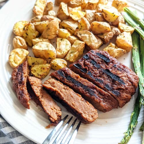 Sliced vegan steak and potatoes on a plate.
