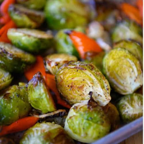 Roasted Brussel Sprouts with Red Peppers and Shallots on a dish.