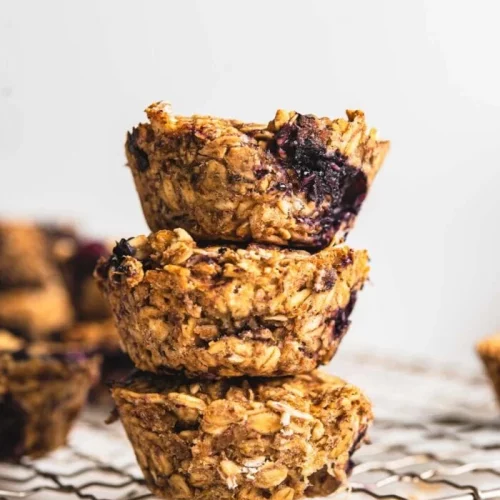 Baked Berry Vegan Oatmeal Cups stacked on a cooling rack.
