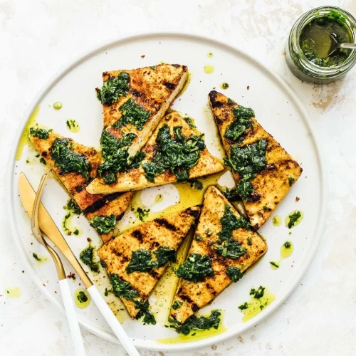 Grilled tofu on a plate with a knife and fork.