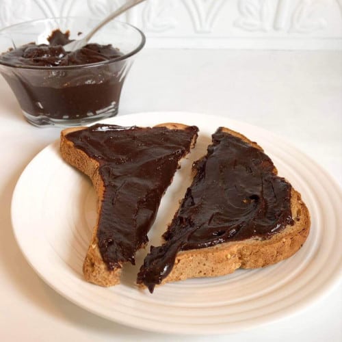 Cokelat bebas kacang tersebar di potongan roti di atas piring.