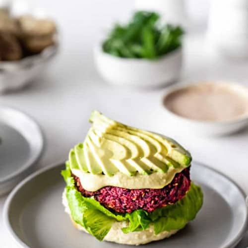 Beet burger on a plate with avocado.