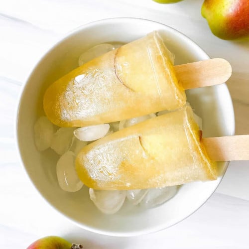 Apple juice popsicles in a bowl of ice cubes.