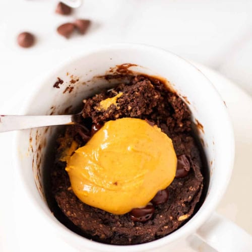 Chocolate protein mug cake in cup with a spoon.