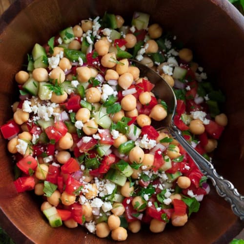Chopped Mediterranean chickpea salad with feta in a wooden bowl.