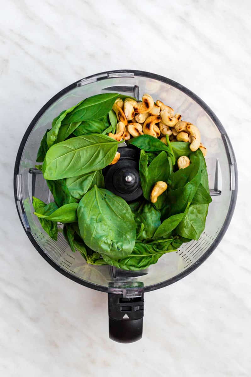 Basil laves and toasted cashews in a food processor.