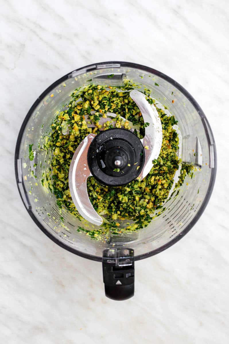 Crumbly pesto mixture in a food processor.
