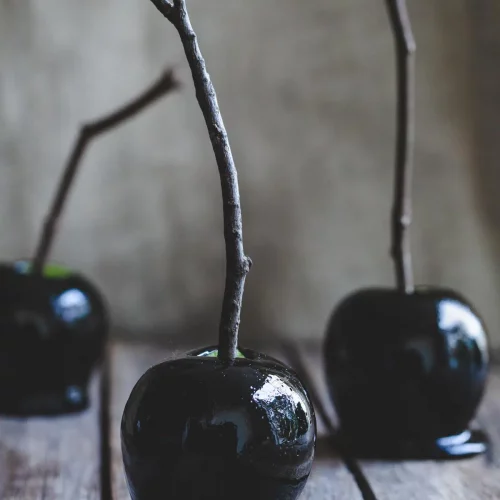 Halloween Toffee Apples on a wood table with sticks.