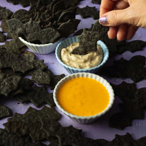 Oil-free Crackers in a bowl and dipping a cracker into dip.