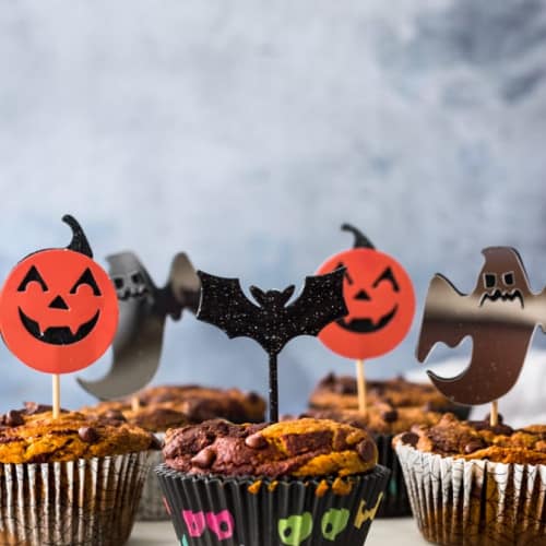 Pumpkin Chocolate Swirl Muffins on a dish with Halloween decorations.