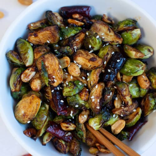 Kung pao brussels sprouts in a bowl with chopsticks.