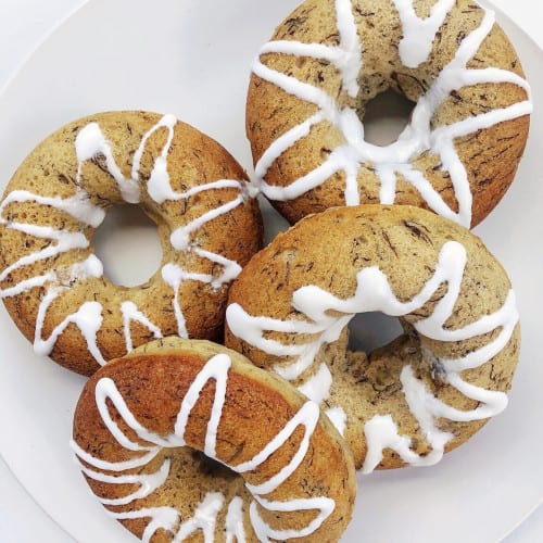 overhead of baked banana bread doughnuts on a white plate.