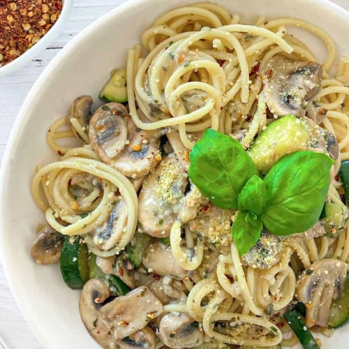 overhead of mushroom and zucchini pasta in a white bowl.