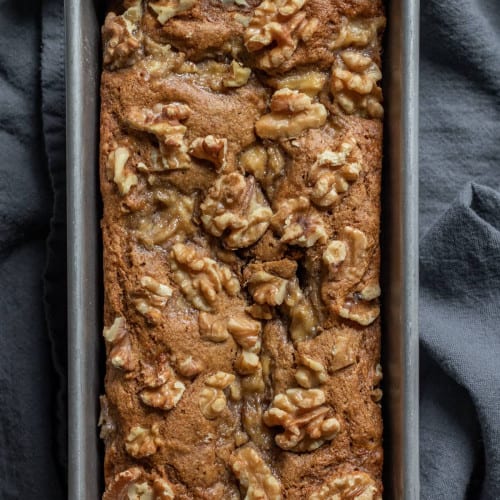 overhead of vegan oat flour banana bread in a loaf pan on a kitchen towel.