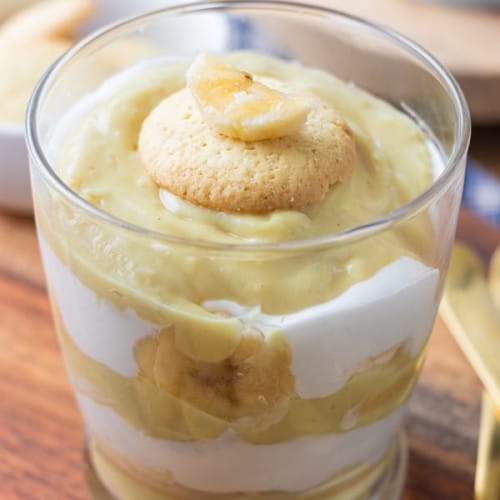 front view of vegan banana pudding in a clear glass on a wooden board.